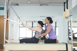 a lady correcting her spine by using clinical pilates