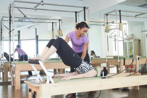 a lady with her legs in the air trying to correct her neck using clinical pilates