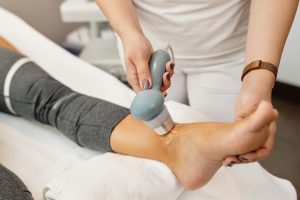 Physio using shockwave therapy on patients ankle